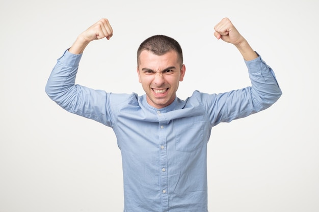 Photo portrait of very excited young hispanic man celebrating victory with raised hands and screaming