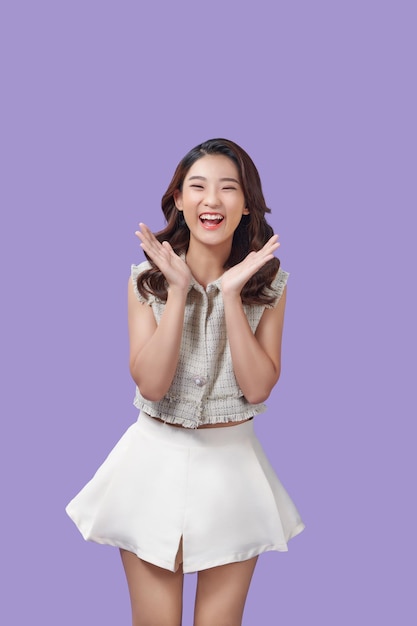 Portrait of very happy jovial laughing beautiful young asian woman isolated against purple background