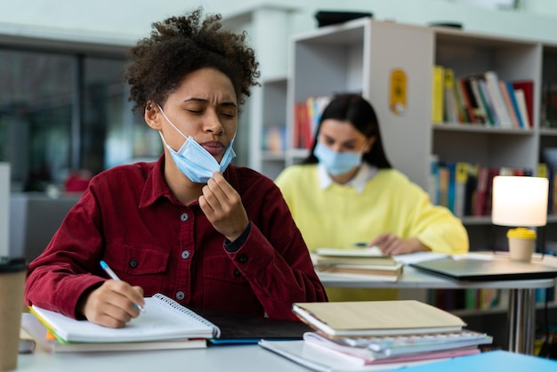 Photo portrait view of the multiracial woman lowers the mask while studying with her classmates at the library during the pandemic