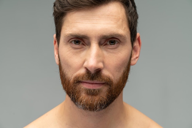 Portrait view of a young handsome naked man posing after taking a shower over the grey wall background Stock photo