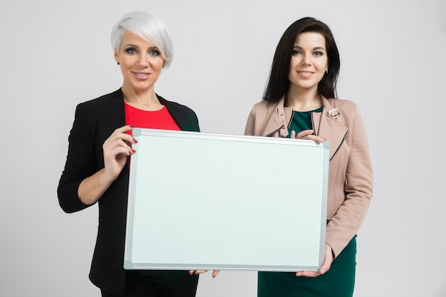 Portrait to the waist Two young girls holding a magnetic Board isolated