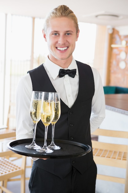 Portrait of waiter holding glasses of champagne