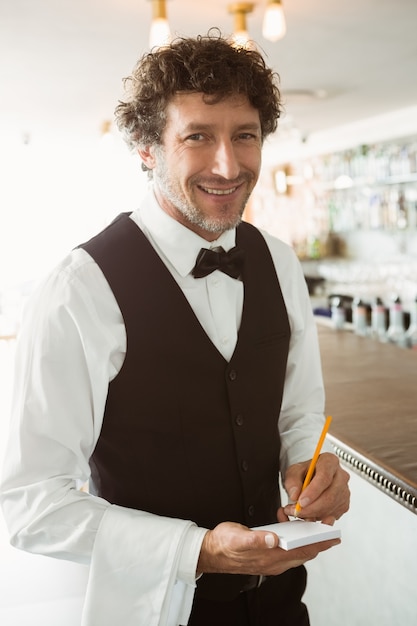 Portrait of waiter holding notepad and pen