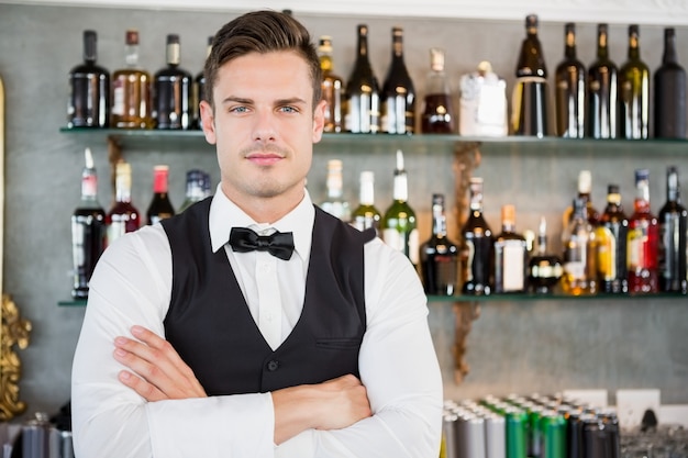 Portrait of waiter standing at bar counter