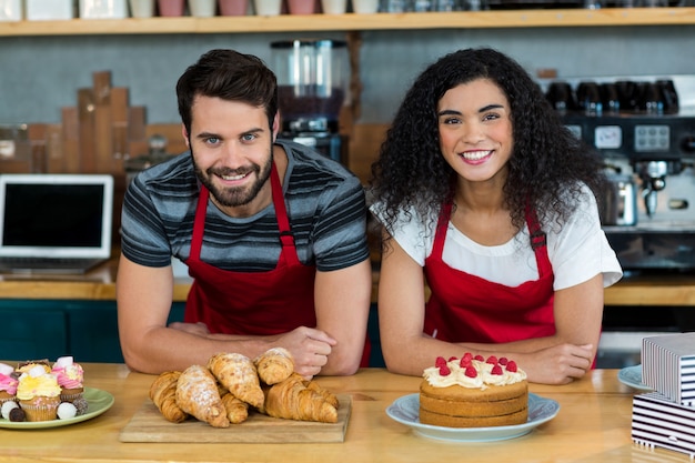 Portrait of waiter and waitress leaning on counter