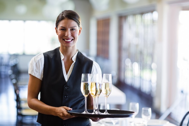 Portrait of waitress holding serving tray with champagne flutesÂ 