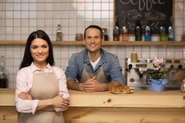 Portrait of waitress with crossed arms standing with barista in coffee shop