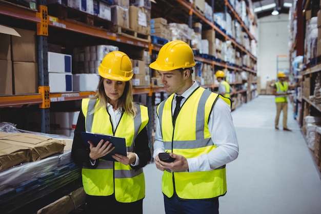 Portrait of warehouse managers looking at clipboard