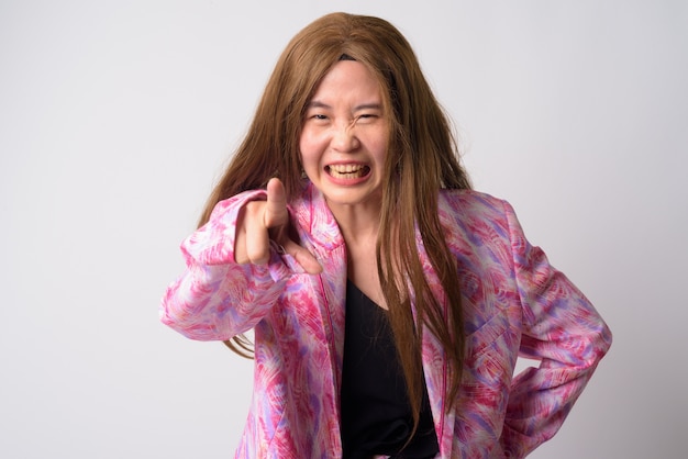 Photo portrait of weird woman wearing pink pantsuit and wig against white wall