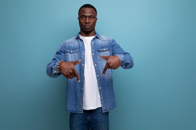 Portrait of a wellgroomed young american man in denim clothes pointing his finger