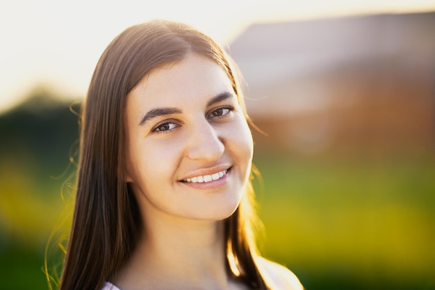 Portrait of white brunette woman in her s in light of setting sun against blurred background of