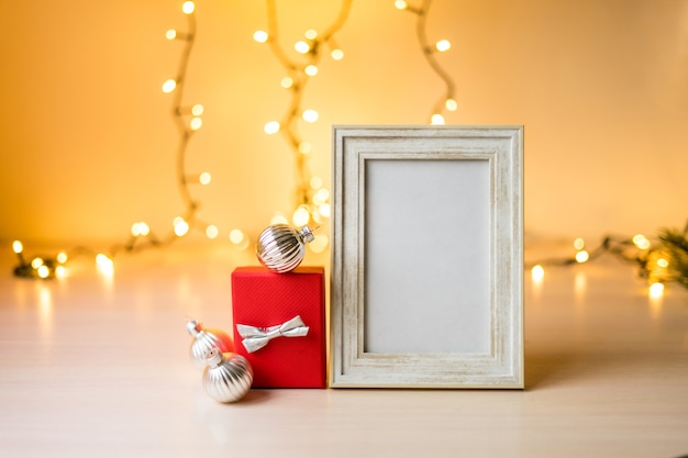 Mockup di cornice bianca ritratto sul tavolo con luci boken e decorazioni natalizie. foto di alta qualità