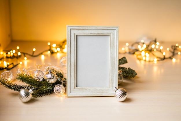 ぼんやりとしたライトとクリスマスの装飾が施されたテーブルの上の肖像画の白い額縁のモックアップ。高品質の写真