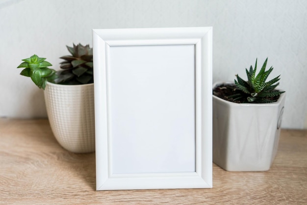 Portrait white picture frame mockup with white pots with succulents and zamiokulkas