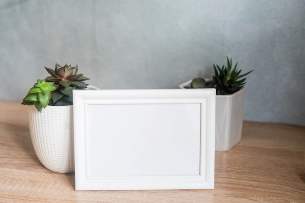 Portrait white picture frame mockup with white pots with succulents and zamiokulkas