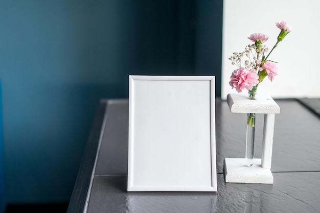 Portrait white picture frame mockup on wooden table . High quality photo
