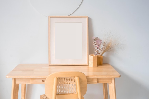 木製のテーブルの上の肖像画の白い額縁のモックアップ。ユーカリを使ったモダンなセラミック花瓶。