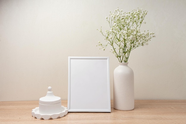 Portrait white picture frame mockup on wooden table Modern ceramic vase with gypsophila