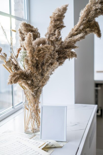 Portrait white picture frame mockup on wooden table with dried flowers. High quality photo