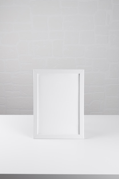 Portrait a whtie wooden frame mockup on the white table on white wall background poster mockup