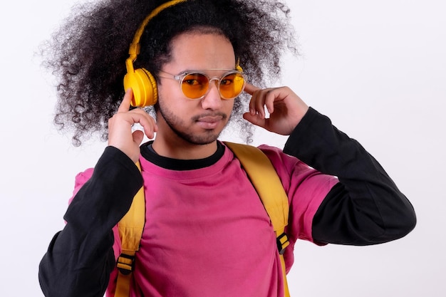 Portrait with pink tshirt and backpack listening to music online Young man with afro hair on white background