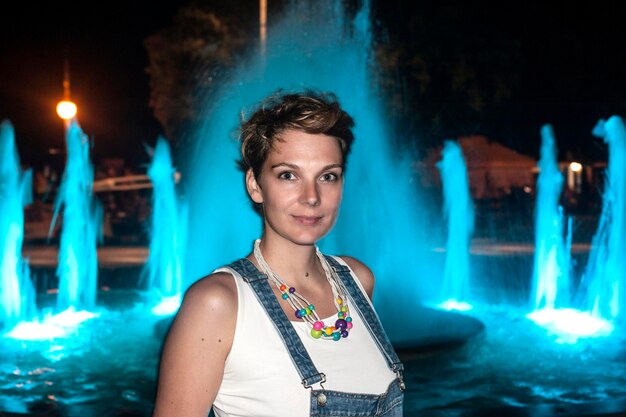 Portrait of woman against blue waterfall at night