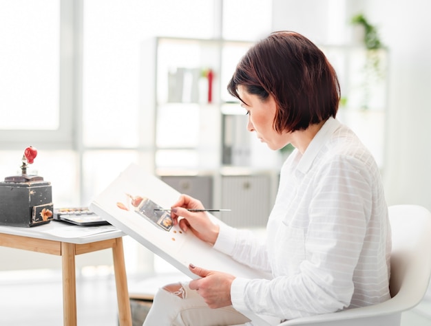 Portrait of woman artist during creative process of drawing with watercolor from nature