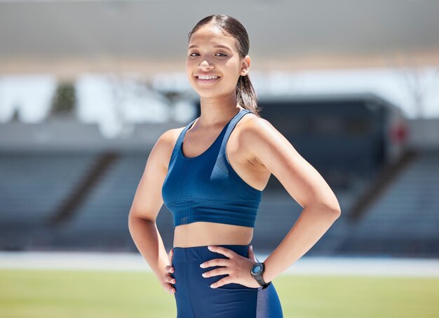 Portrait woman and athlete on stadium running track for sports race arena and outdoor competition Happy young runner ready for marathon event exercise motivation and training goals in sunshine