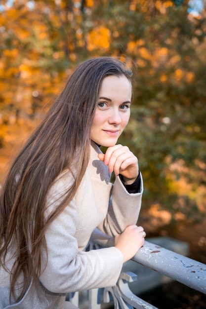 Portrait of a woman in autumn park with falling leaves