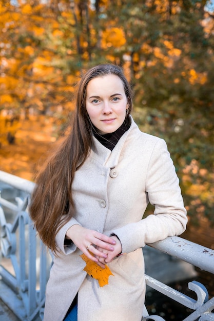 Portrait of a woman in autumn park with falling leaves