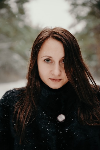 Portrait of a woman on the background of a snowy forest