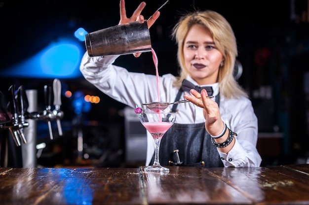 Photo portrait of woman barman demonstrates his skills over the counter in the nightclub