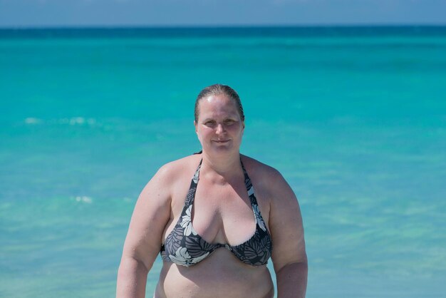 Portrait of woman in bikini top standing against sea