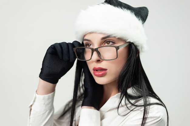 안경과 검은색 산타 모자를 쓴 검은색 비즈니스 정장을 입은 여성의 초상화