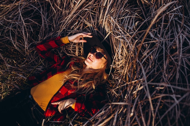 Foto ritratto di una donna con un cappello nero attraverso la foresta di autunno