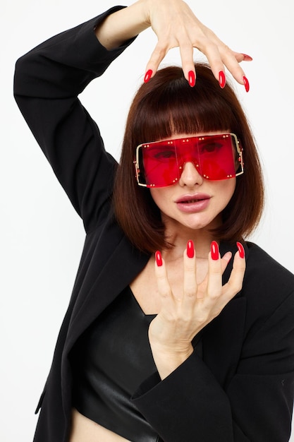 Portrait of a woman in a black jacket red nail polish fashion glasses light background