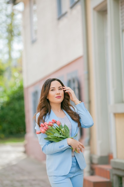 Portrait of a woman in a blue suit with a bouquet of tulips