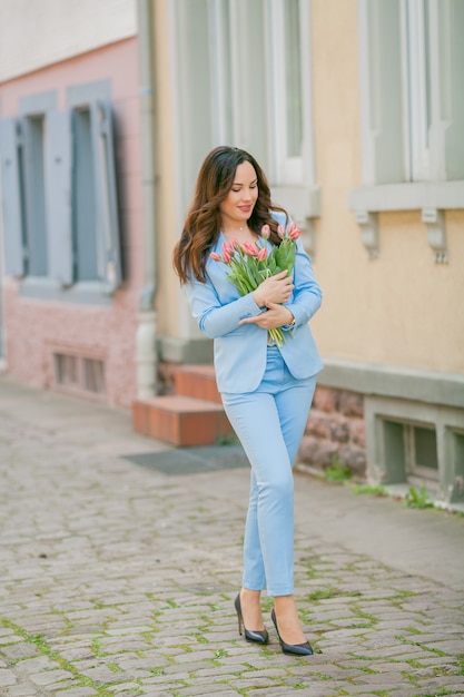 Portrait of a woman in a blue suit with a bouquet of tulips