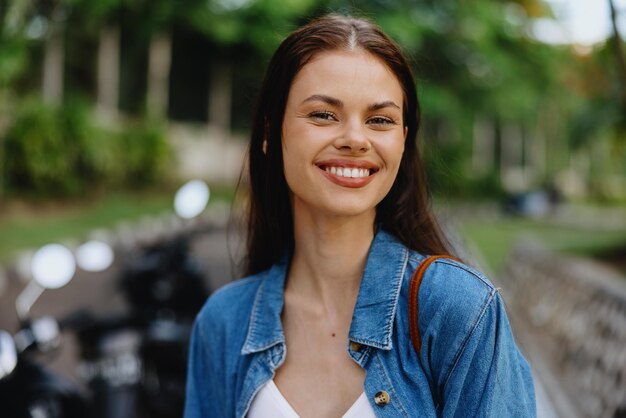 Photo portrait of a woman brunette smile with teeth walking outside against a backdrop of palm trees in the tropics summer vacations and outdoor recreation the carefree lifestyle of a freelance student