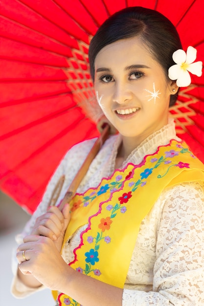 Portrait woman in Burmese's local costume, is carrying a red umbrella.