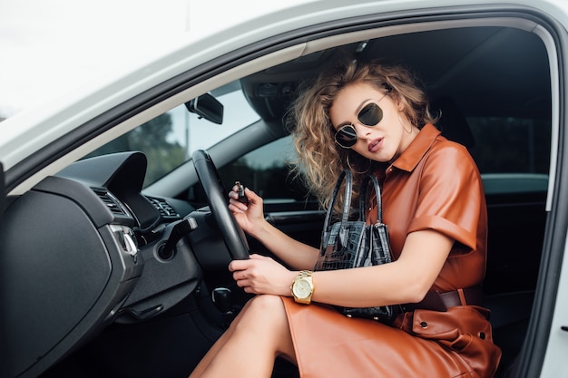 Portrait of woman in car in car salon with key in hand