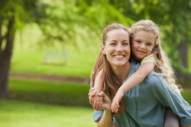 Portrait of woman carrying girl at park