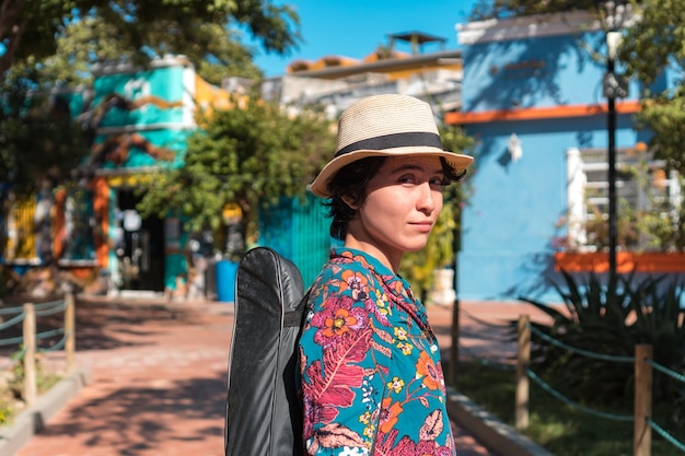 Portrait of woman carrying a guitar with its case in the park