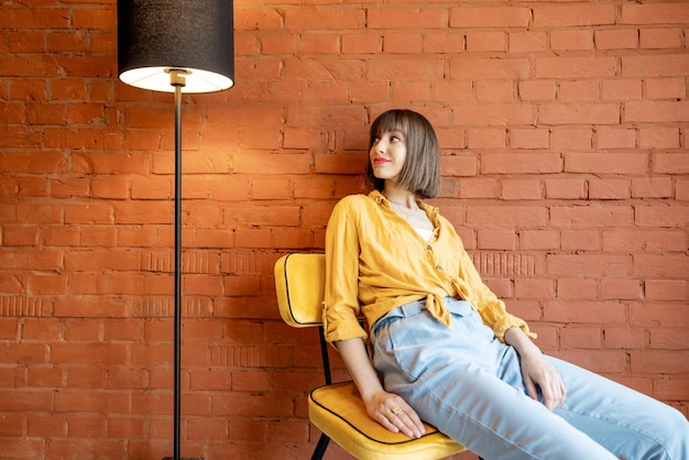 Portrait of a woman on chair on brick wall background