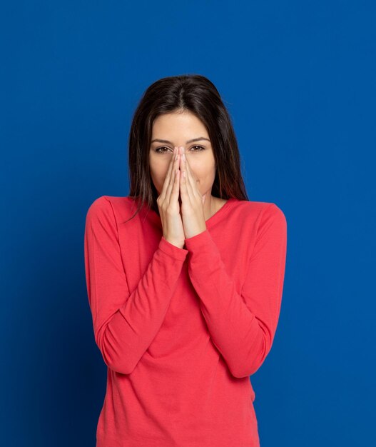 Portrait of woman covering face against blue background