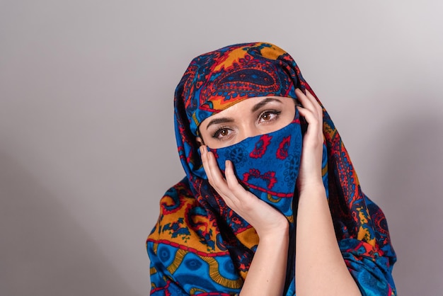 Portrait of woman covering face against gray background