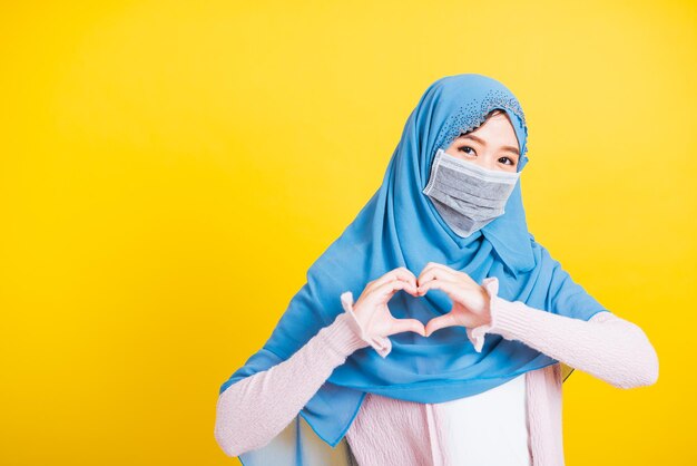 Portrait of a woman covering face against yellow background