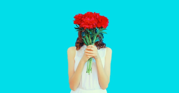 Portrait of woman covering her head with bouquet of red rose flowers