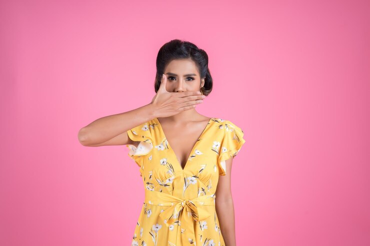फोटो portrait of woman covering mouth against pink background