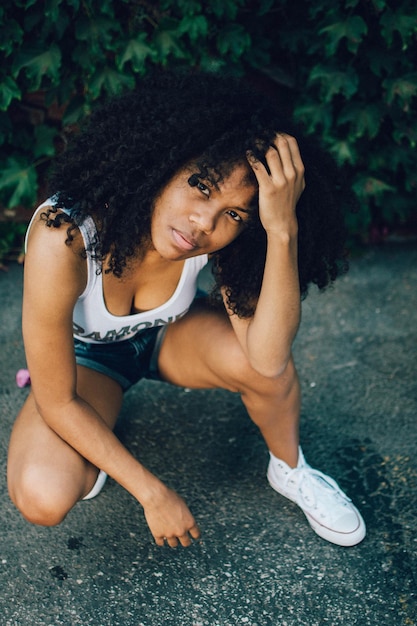 portrait of woman crouching on footpath at park